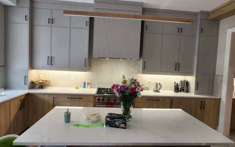 Finished GTA kitchen with painted cabinet doors above and wood-veneer drawer fronts below, quartz counter and gas range