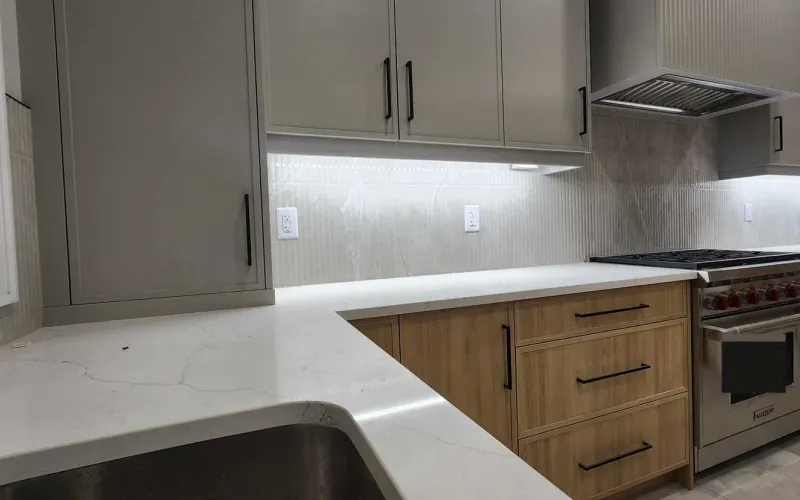 L-shaped GTA kitchen with a white veined countertop around an undermount sink, oak-look lower drawers and a gas range