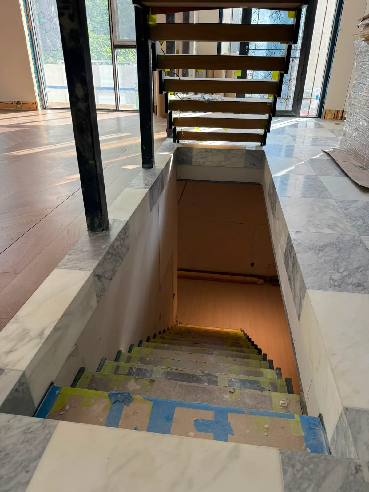 Marble-edged opening with a protected staircase going down to the lower floor and an open-tread stair above