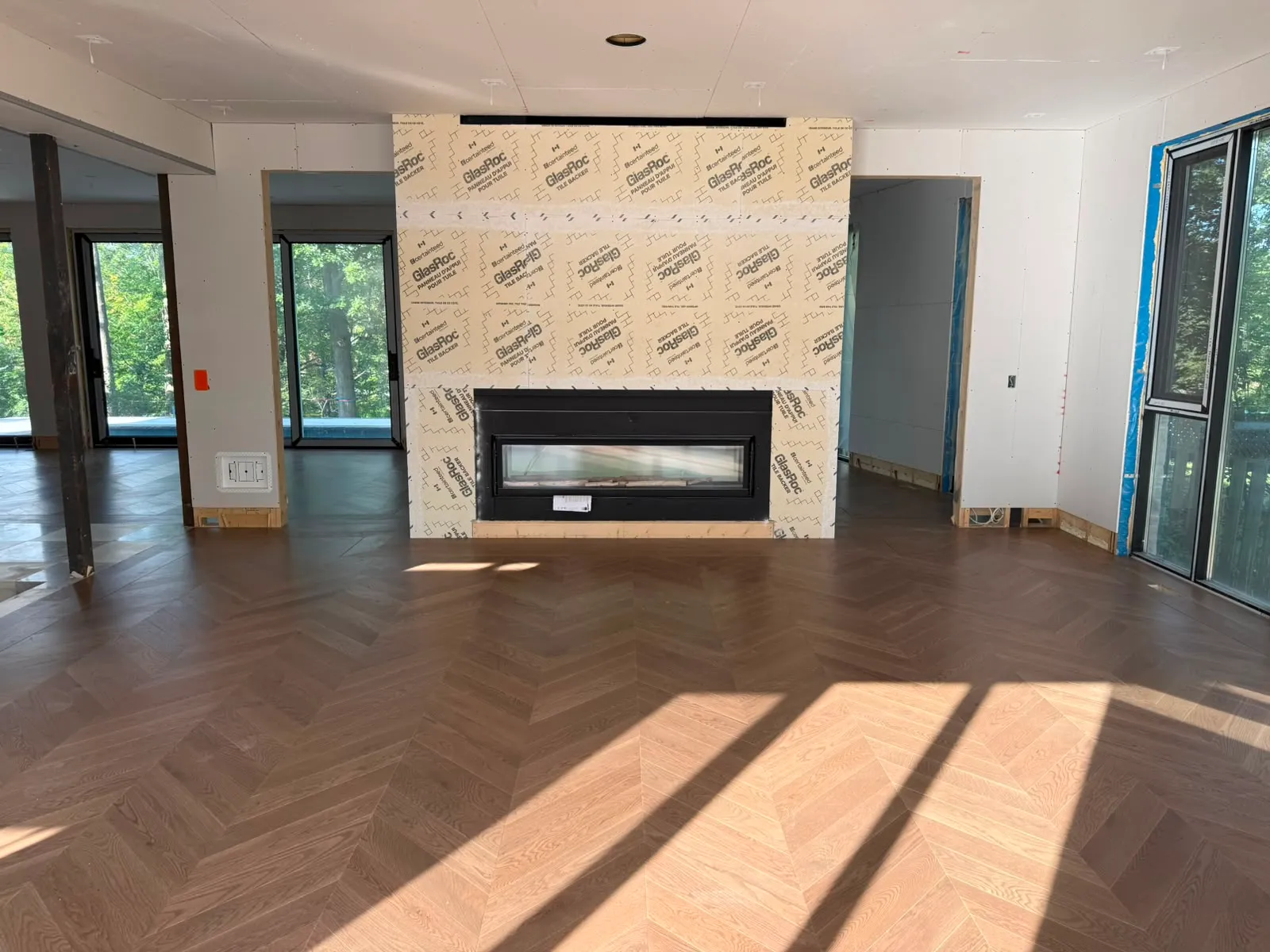 Linear fireplace insert installed in a wall covered with tile backer board above oak herringbone flooring