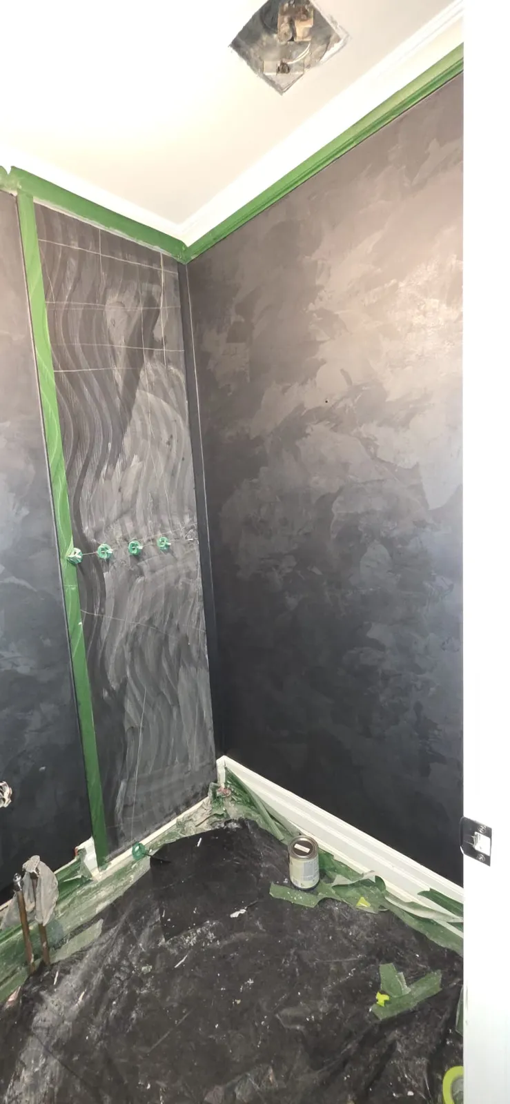 Dark finish on two washroom walls with a patterned back panel taped along both edges in green tape