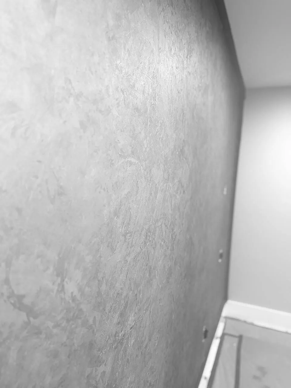 Close view of the grey troweled finish running into a white painted corner