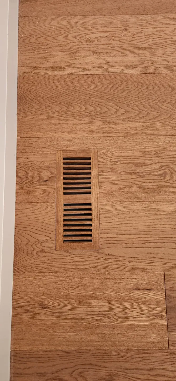 Oak floor vent grille set flush into an oak plank floor