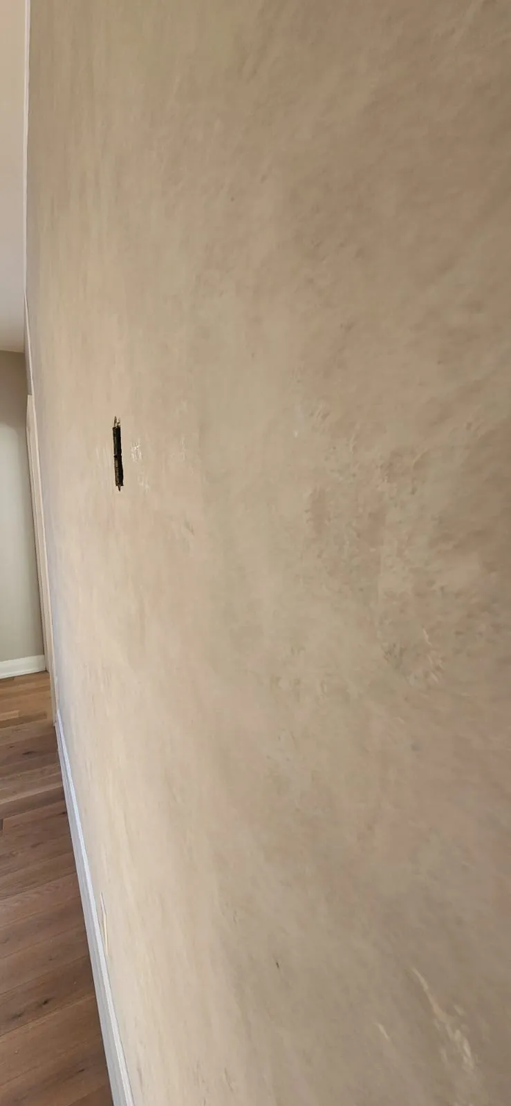 Smooth beige plaster wall with one small box opening near the top